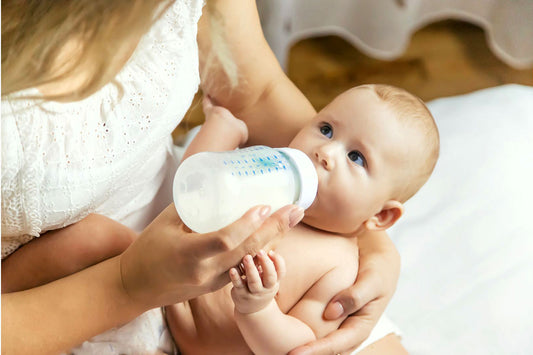 Infant being fed with milk heated in a baby bottle warmer